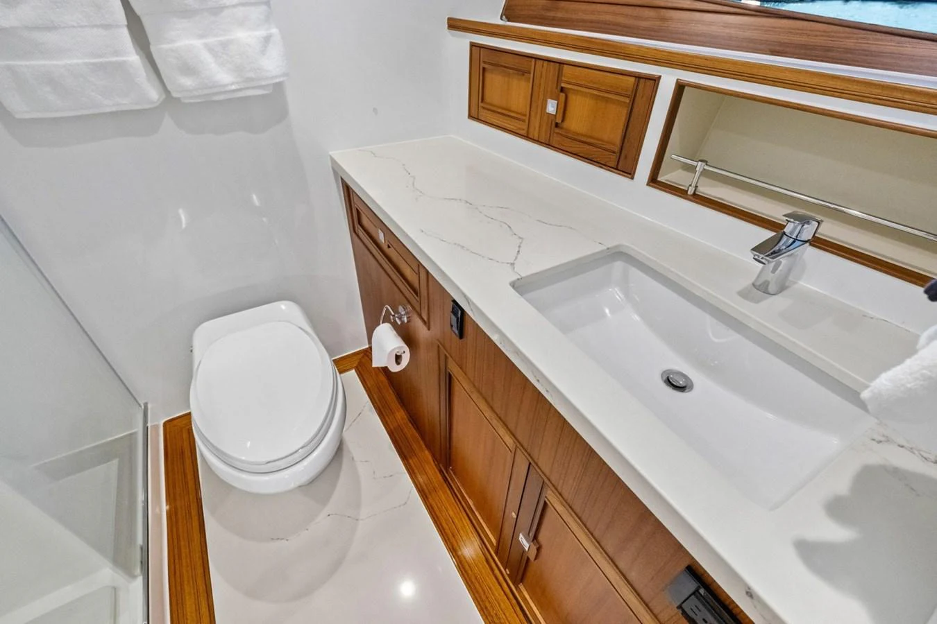 The yacht's bathroom features elegant wood cabinetry and a sleek white countertop with a modern sink. aboard ARTEMIS II Yacht for Sale