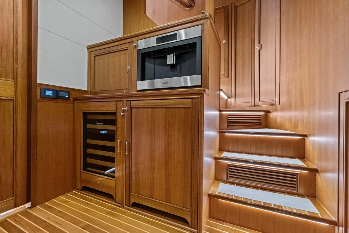 The galley features warm wood cabinetry, a built-in coffee machine, and a wine cooler, complemented by sleek stairs leading to the upper deck. aboard ARTEMIS II Yacht for Sale