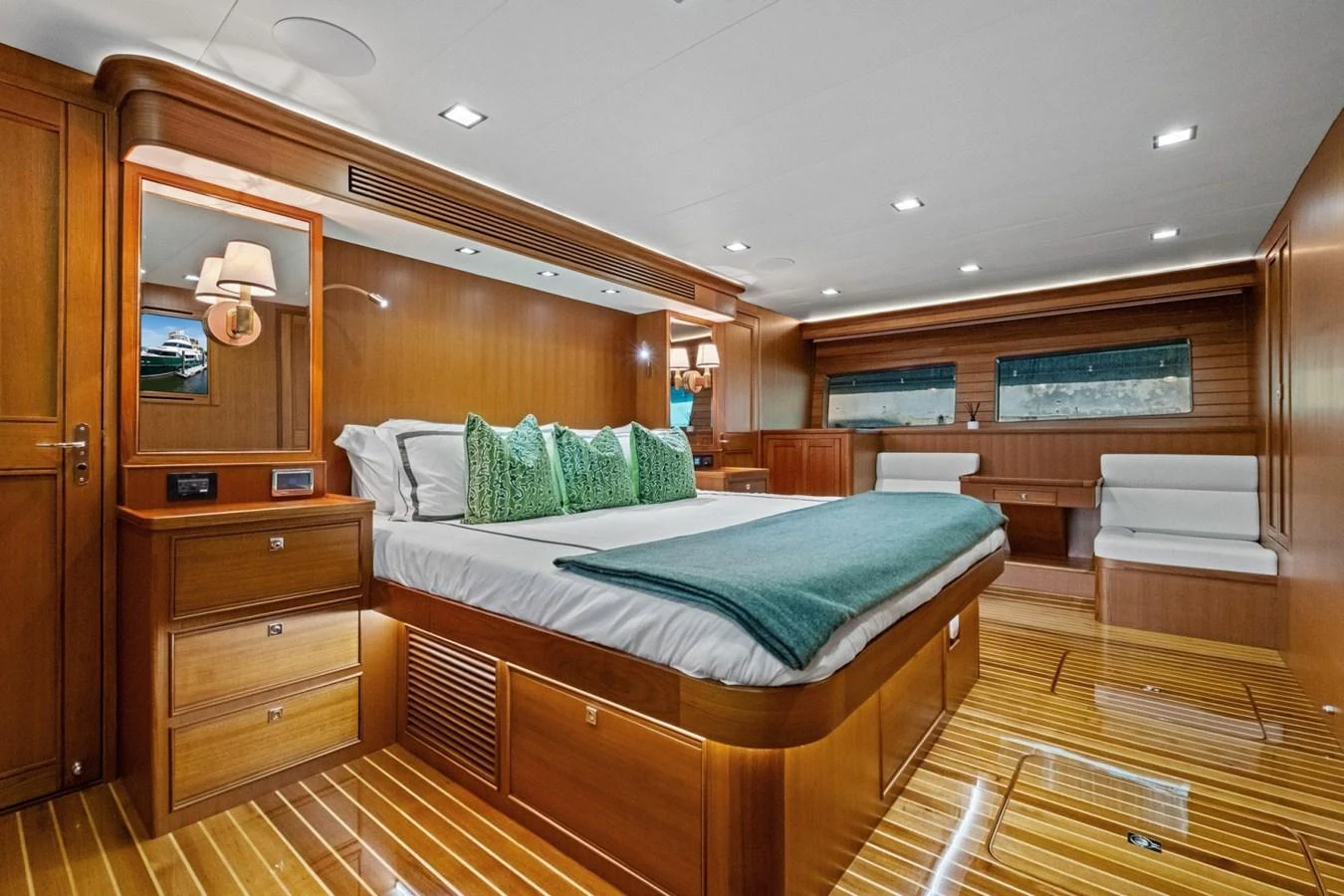 The stateroom features a luxurious bed with elegant wooden furnishings and ample natural light. aboard ARTEMIS II Yacht for Sale