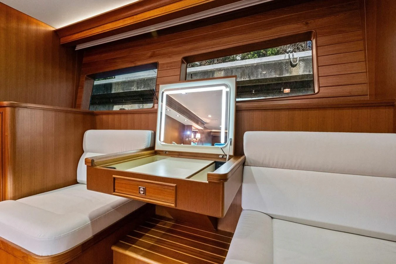 The yacht's interior features a cozy seating area with a built-in vanity and ample natural light from the windows. aboard ARTEMIS II Yacht for Sale