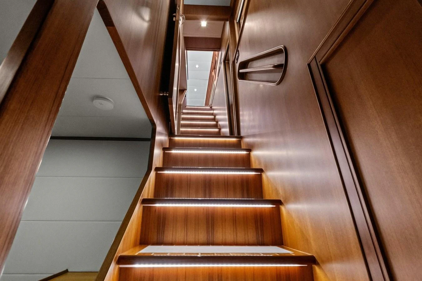 A beautifully crafted wooden staircase with ambient lighting leads to the upper deck. aboard ARTEMIS II Yacht for Sale