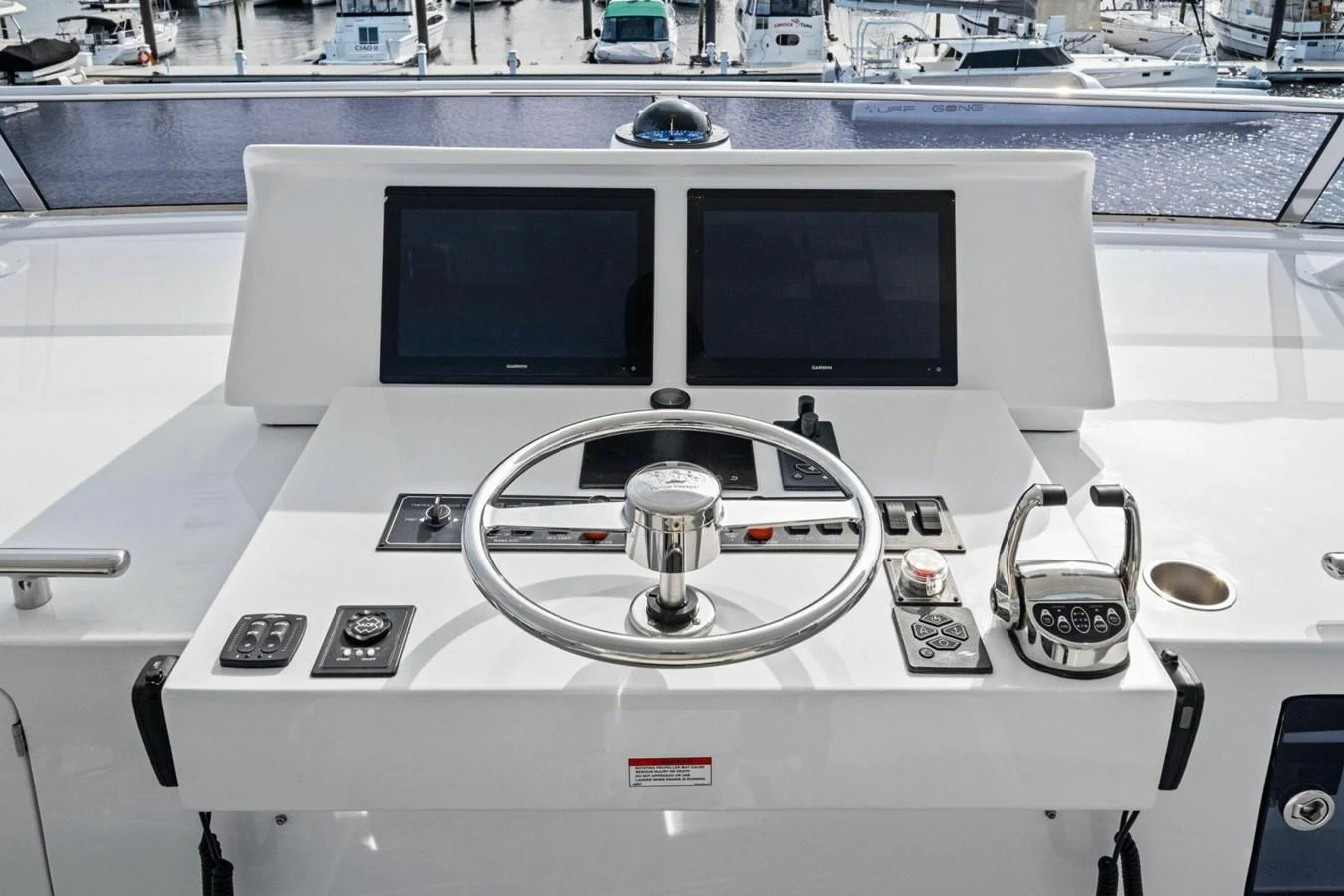 The helm station features modern navigation equipment and a sleek steering wheel, offering a commanding view of the marina. aboard ARTEMIS II Yacht for Sale