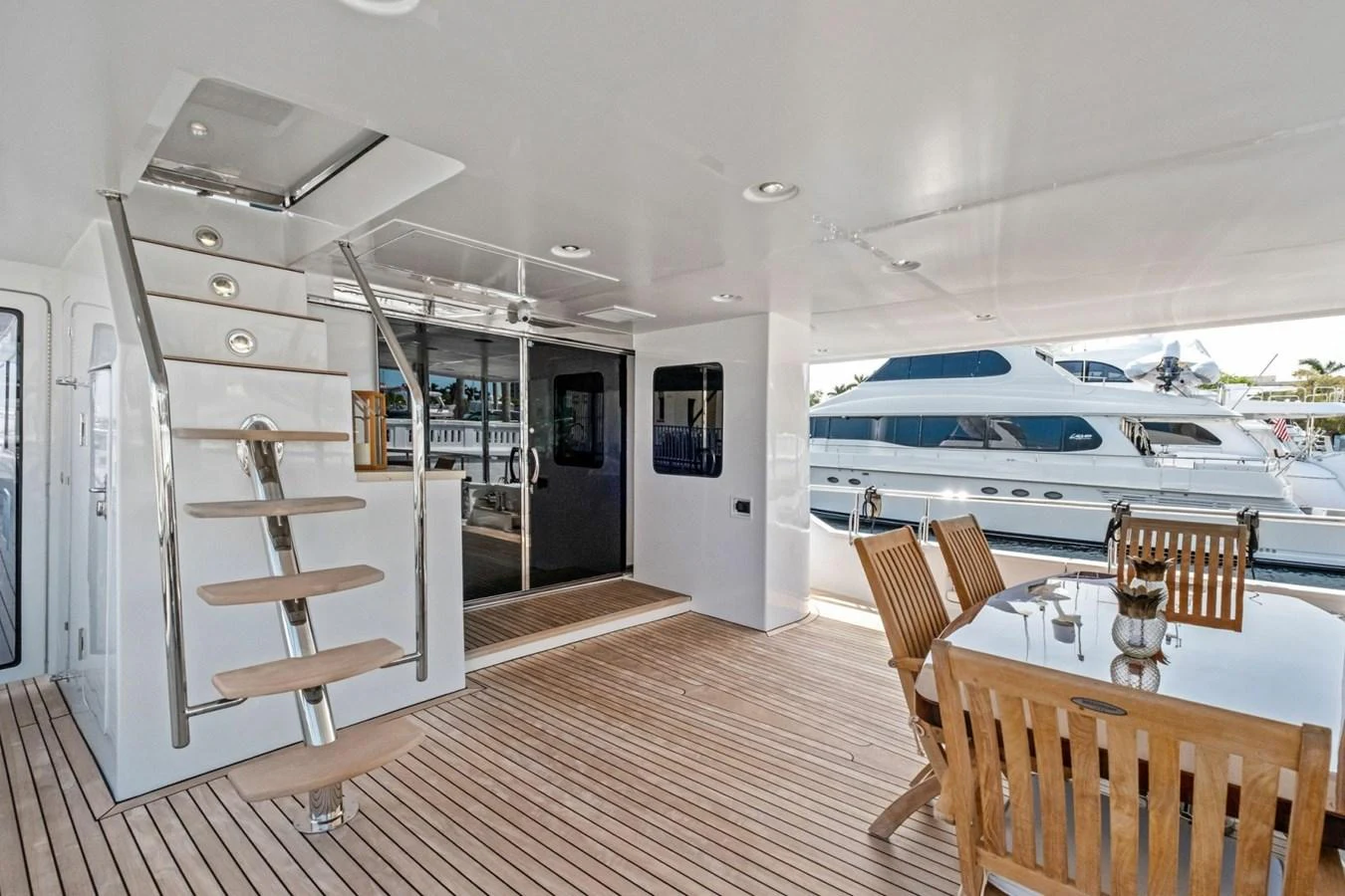 The aft deck features a spacious dining area with wooden furniture and a staircase leading to the upper deck. aboard ARTEMIS II Yacht for Sale