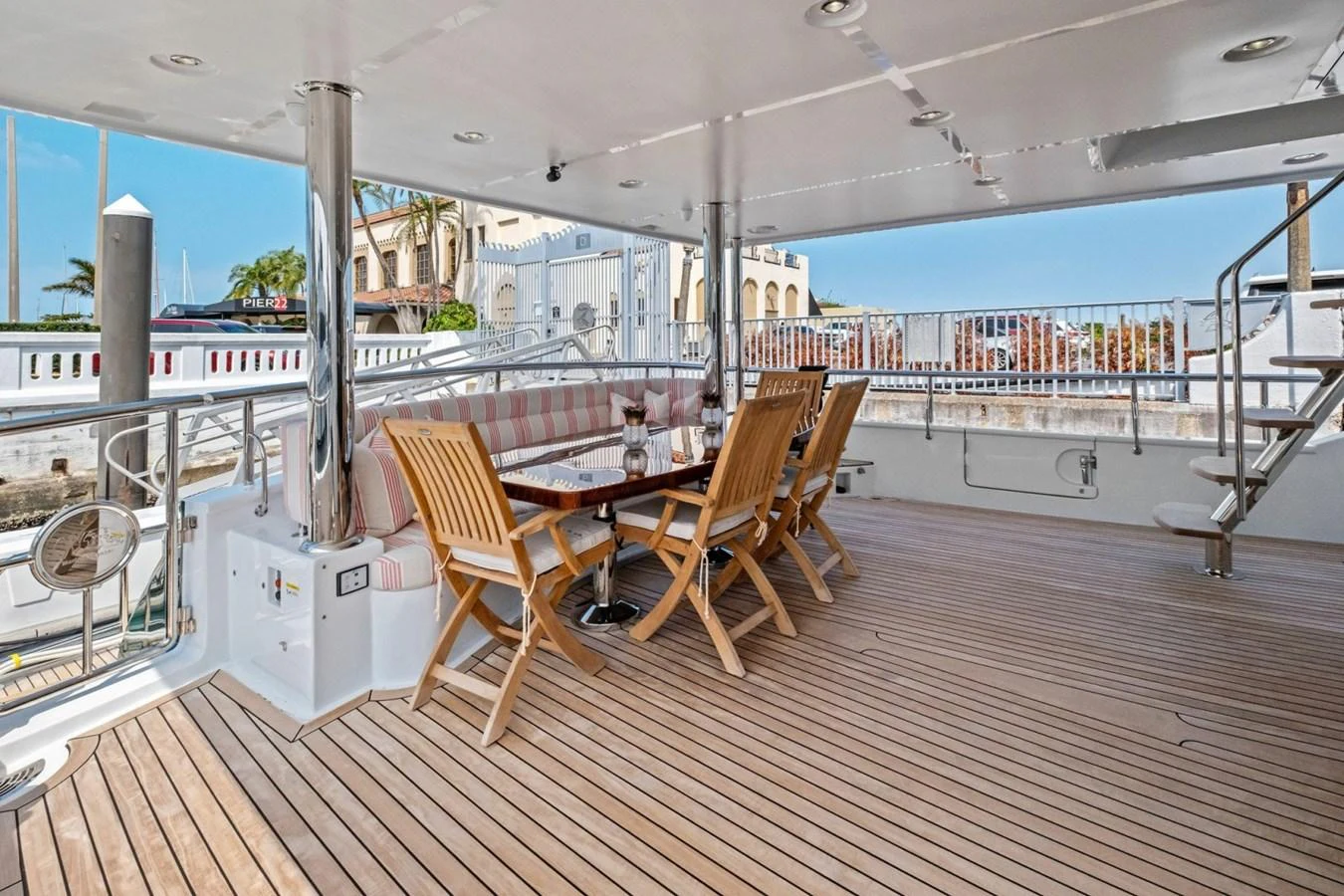 The aft deck features a spacious seating area with wooden chairs and a dining table, perfect for outdoor meals and relaxation. aboard ARTEMIS II Yacht for Sale