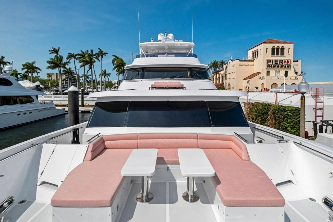 The yacht's foredeck features a spacious seating area with pink cushions and two tables, perfect for relaxing and enjoying the view. aboard ARTEMIS II Yacht for Sale