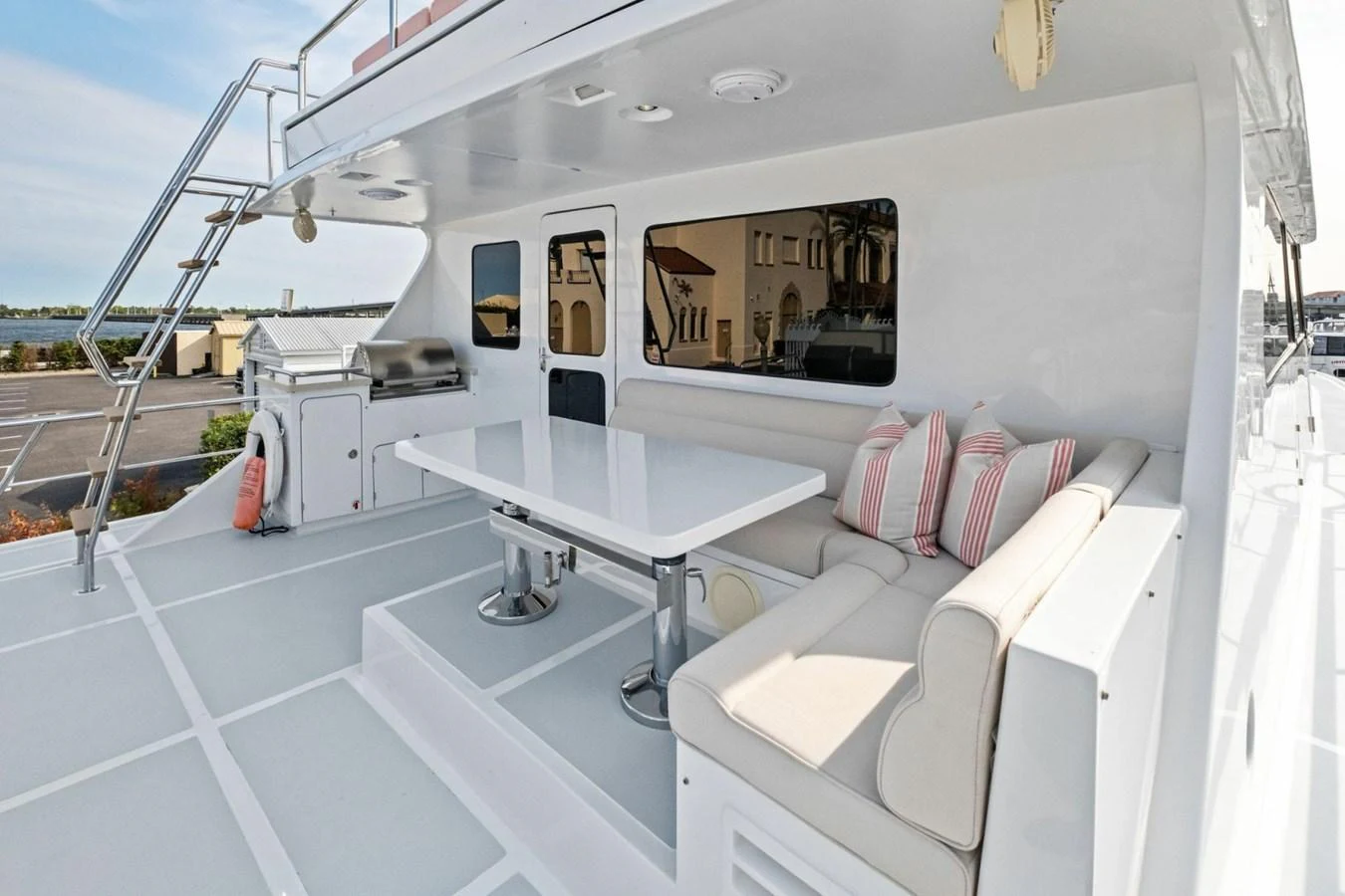 The aft deck features a comfortable seating area with a dining table and a grill station. aboard ARTEMIS II Yacht for Sale