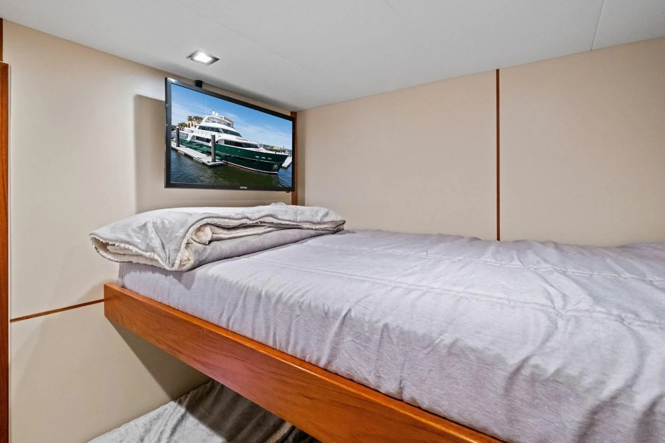 A cozy cabin featuring a comfortable bed and a wall-mounted TV displaying a yacht. aboard ARTEMIS II Yacht for Sale