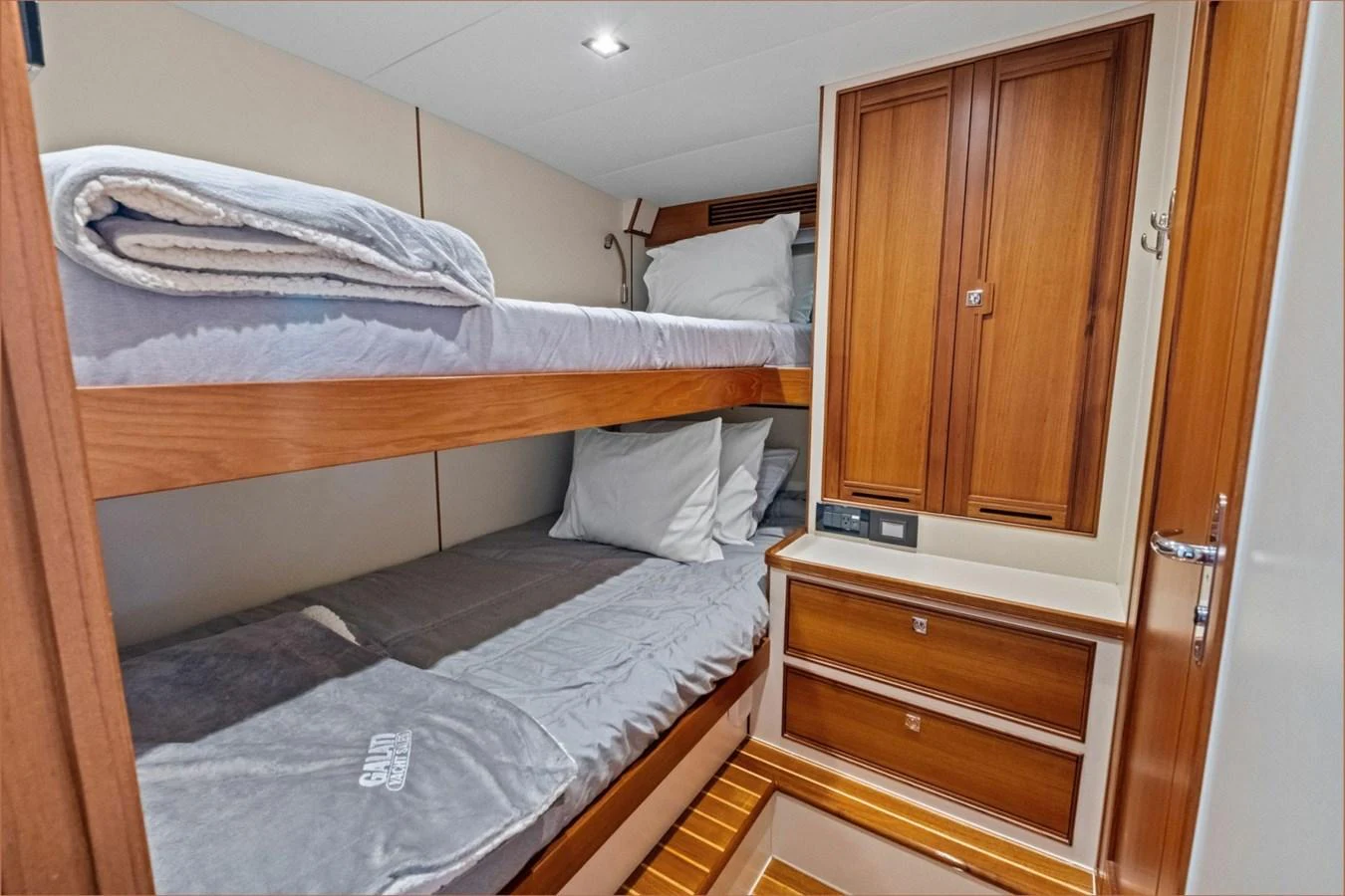 The guest cabin features cozy bunk beds with warm wooden cabinetry and ample storage. aboard ARTEMIS II Yacht for Sale