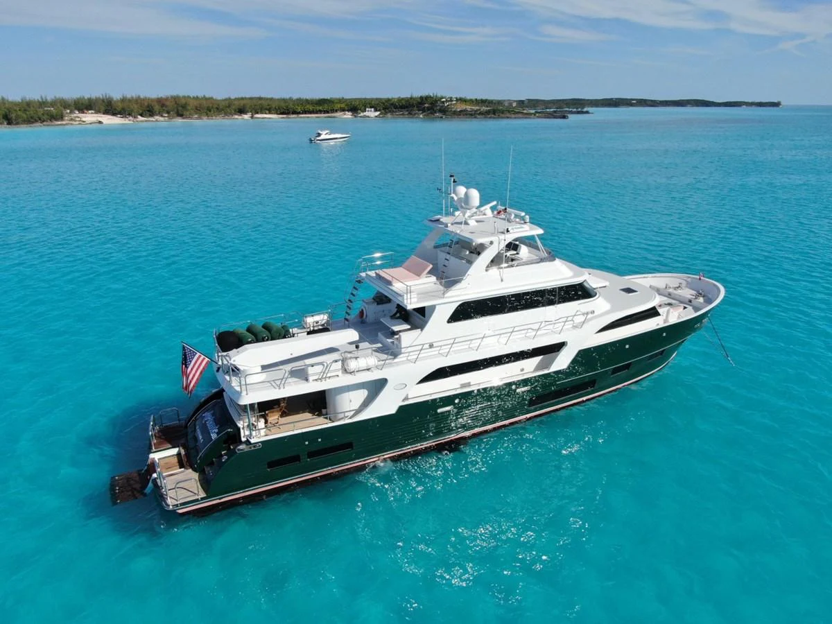 A luxurious yacht cruises through crystal-clear turquoise waters with a serene backdrop of distant islands. aboard ARTEMIS II Yacht for Sale