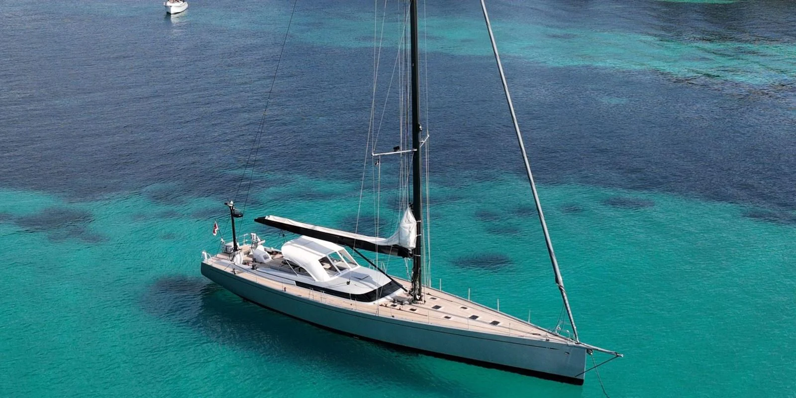 A sleek sailing yacht glides gracefully on clear turquoise waters. aboard LA LOEVIE Yacht for Sale