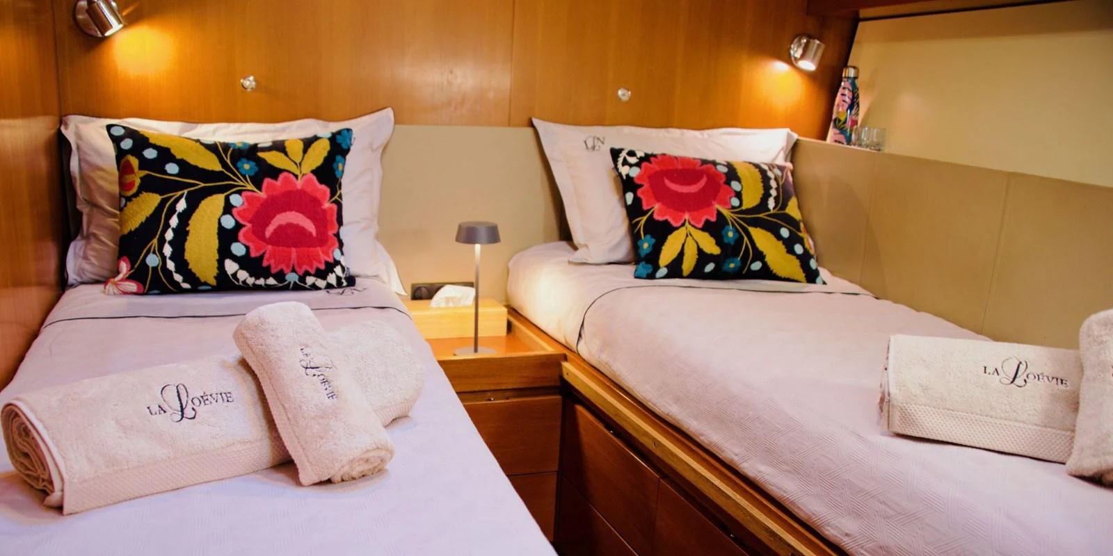 The twin stateroom features cozy beds with vibrant floral pillows and soft lighting, creating a welcoming atmosphere. aboard LA LOEVIE Yacht for Sale