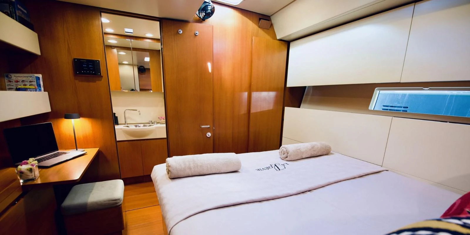 The stateroom features a cozy bed, a work desk, and elegant wooden finishes. aboard LA LOEVIE Yacht for Sale