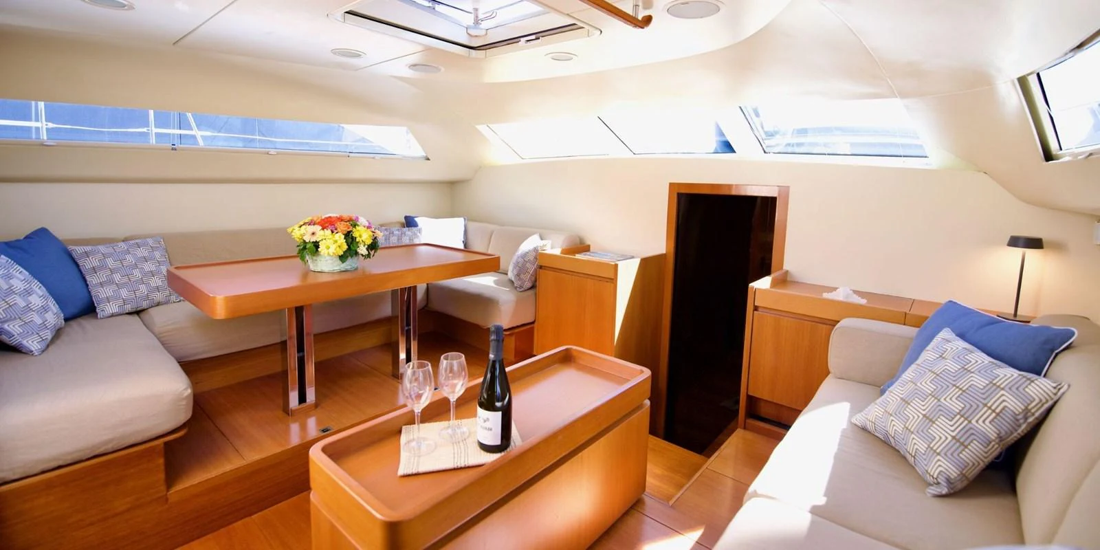 The salon features a cozy seating area with a dining table, complemented by natural light from the windows and skylight. aboard LA LOEVIE Yacht for Sale