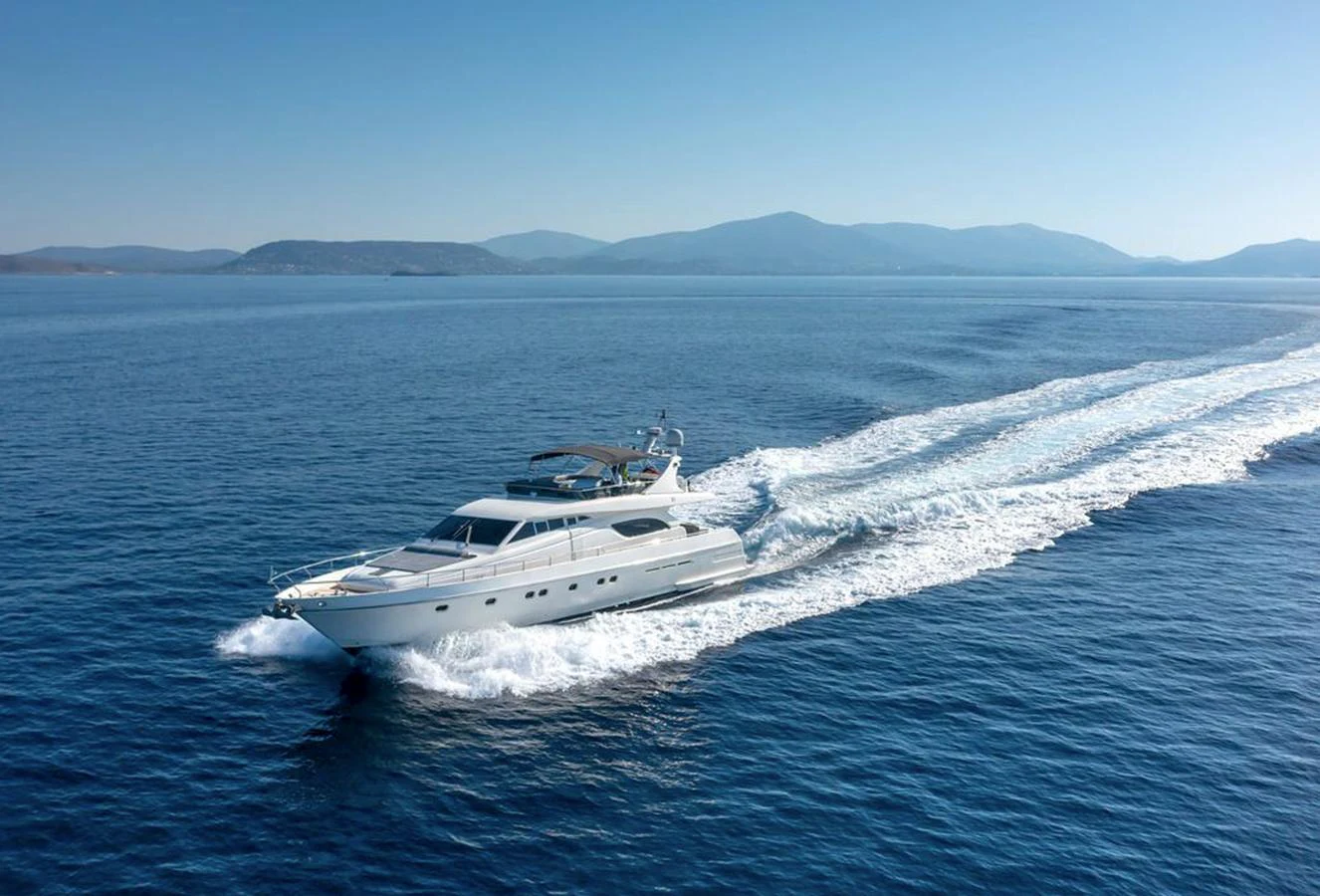 A sleek yacht cruises swiftly across calm blue waters with a scenic mountainous backdrop. aboard FERRETTI 810/78 Yacht for Sale