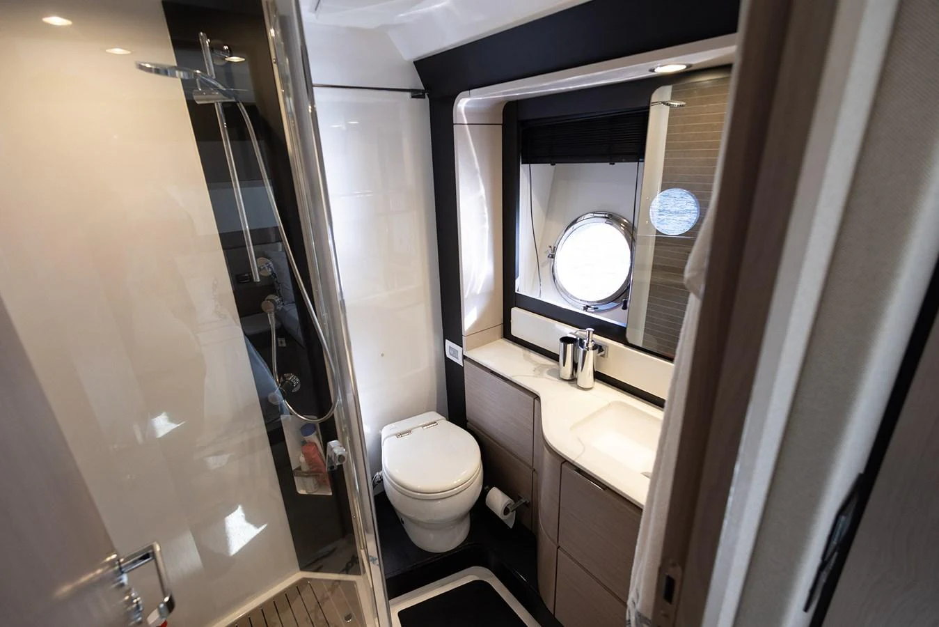The yacht's bathroom is sleek and modern, featuring a glass-enclosed shower and a porthole window. aboard AZ FLY 66 Yacht for Sale