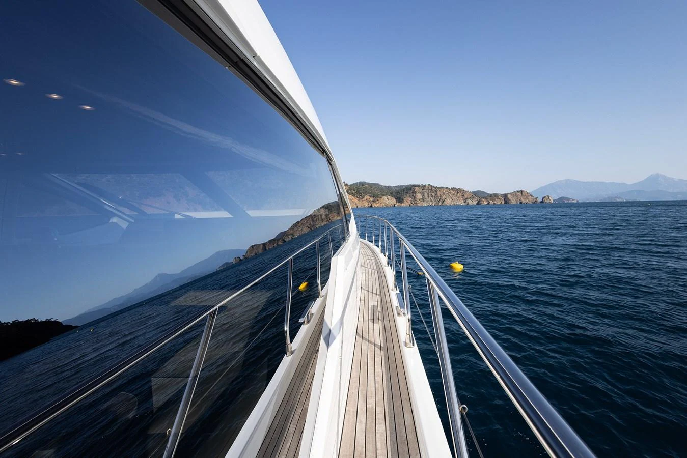 A sleek yacht glides through calm waters with a scenic coastline in the background. aboard AZ FLY 66 Yacht for Sale