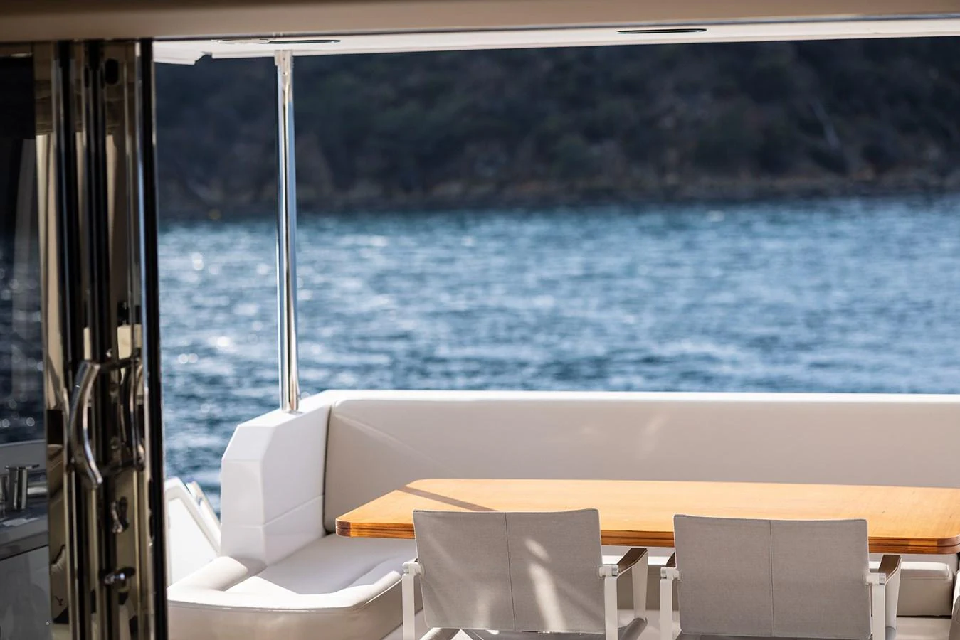 The aft deck features a stylish dining area with a wooden table and comfortable seating, offering a serene view of the water. aboard AZ FLY 66 Yacht for Sale