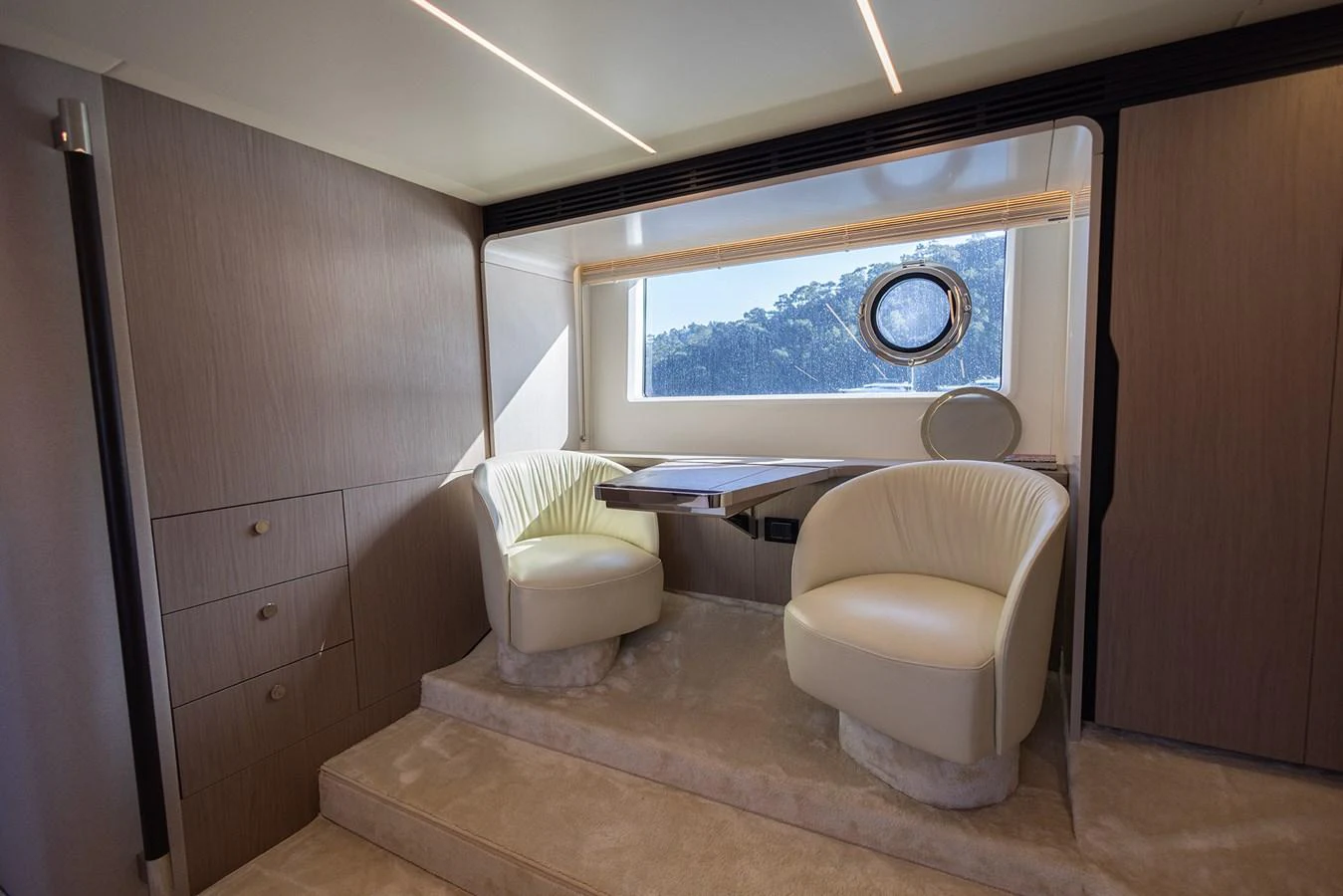 A cozy seating area with two plush chairs and a small table, bathed in natural light from a large window. aboard AZ FLY 66 Yacht for Sale