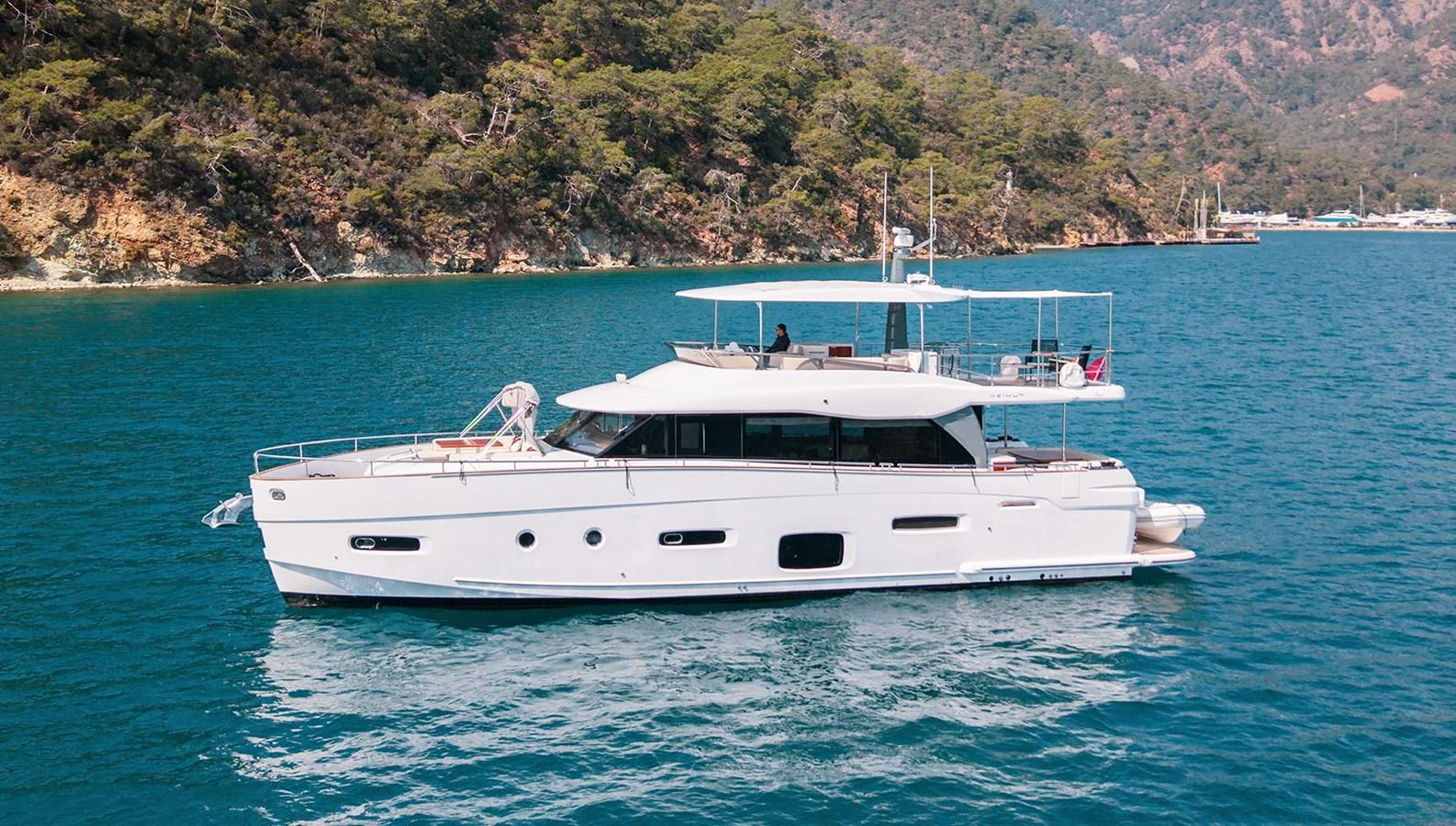 A sleek white yacht cruising in serene blue waters with a lush green coastline in the background. aboard AZ MAGELLANO 66 Yacht for Sale