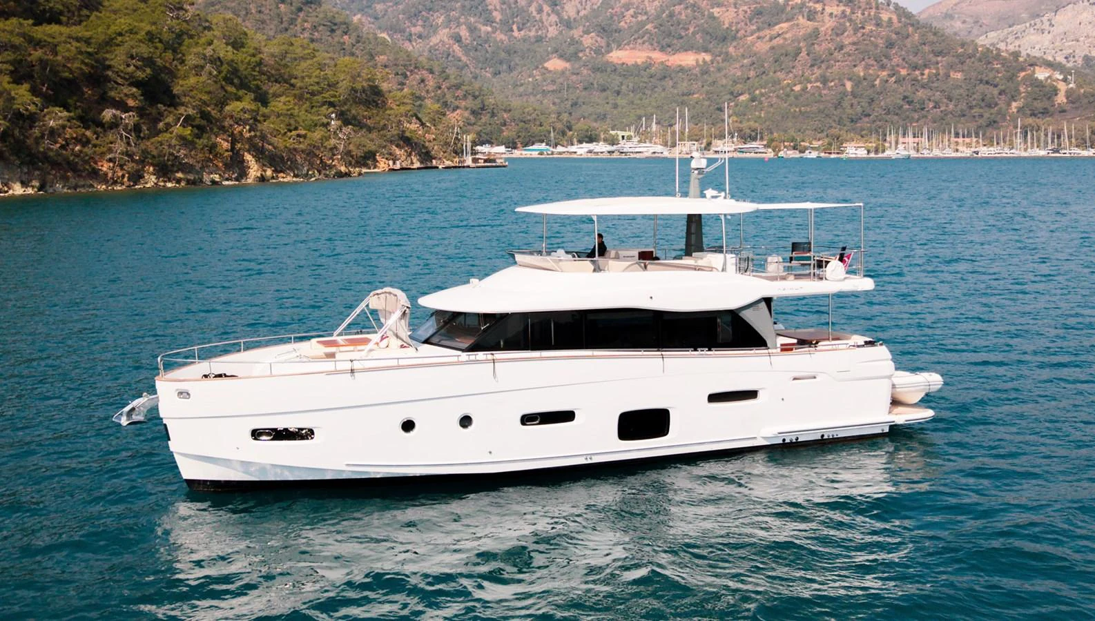 A sleek white yacht glides gracefully on calm blue waters with a scenic mountainous backdrop. aboard AZ MAGELLANO 66 Yacht for Sale