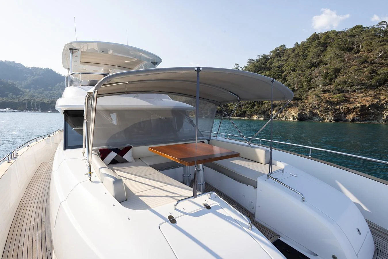 The yacht's flybridge offers a shaded seating area with a wooden table, perfect for enjoying scenic views. aboard AZ MAGELLANO 66 Yacht for Sale