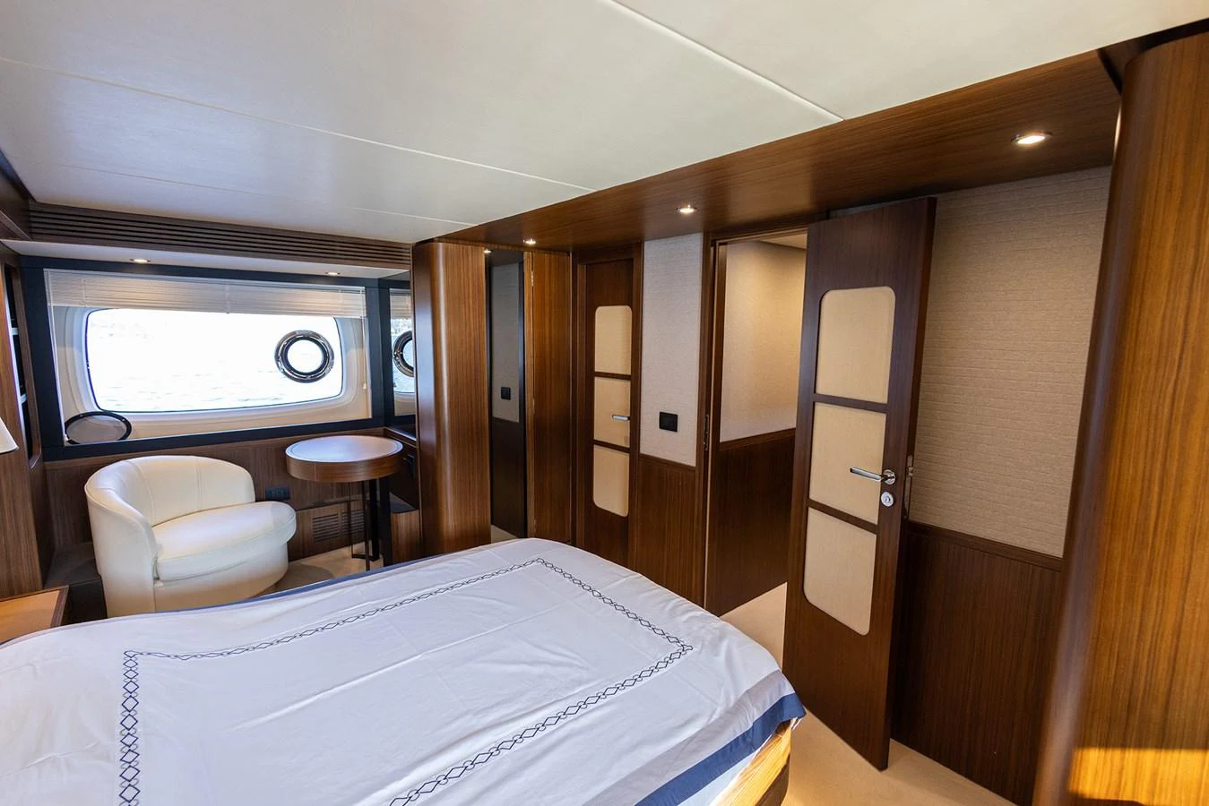 The stateroom features elegant wood paneling, a comfortable bed, and a cozy seating area by the window. aboard AZ MAGELLANO 66 Yacht for Sale