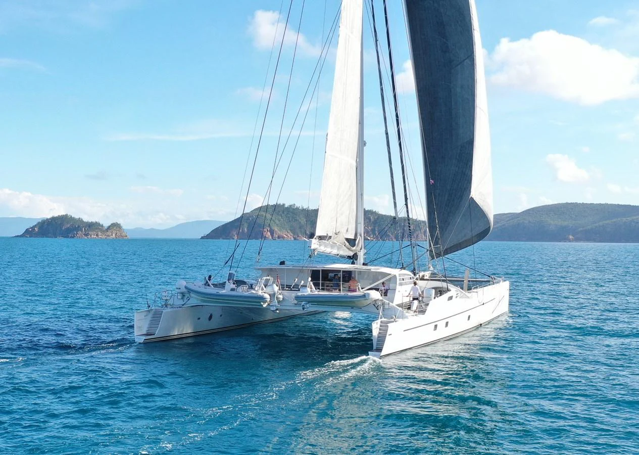 A sleek catamaran glides gracefully on the open sea under clear blue skies. aboard VITALIA II Yacht for Sale