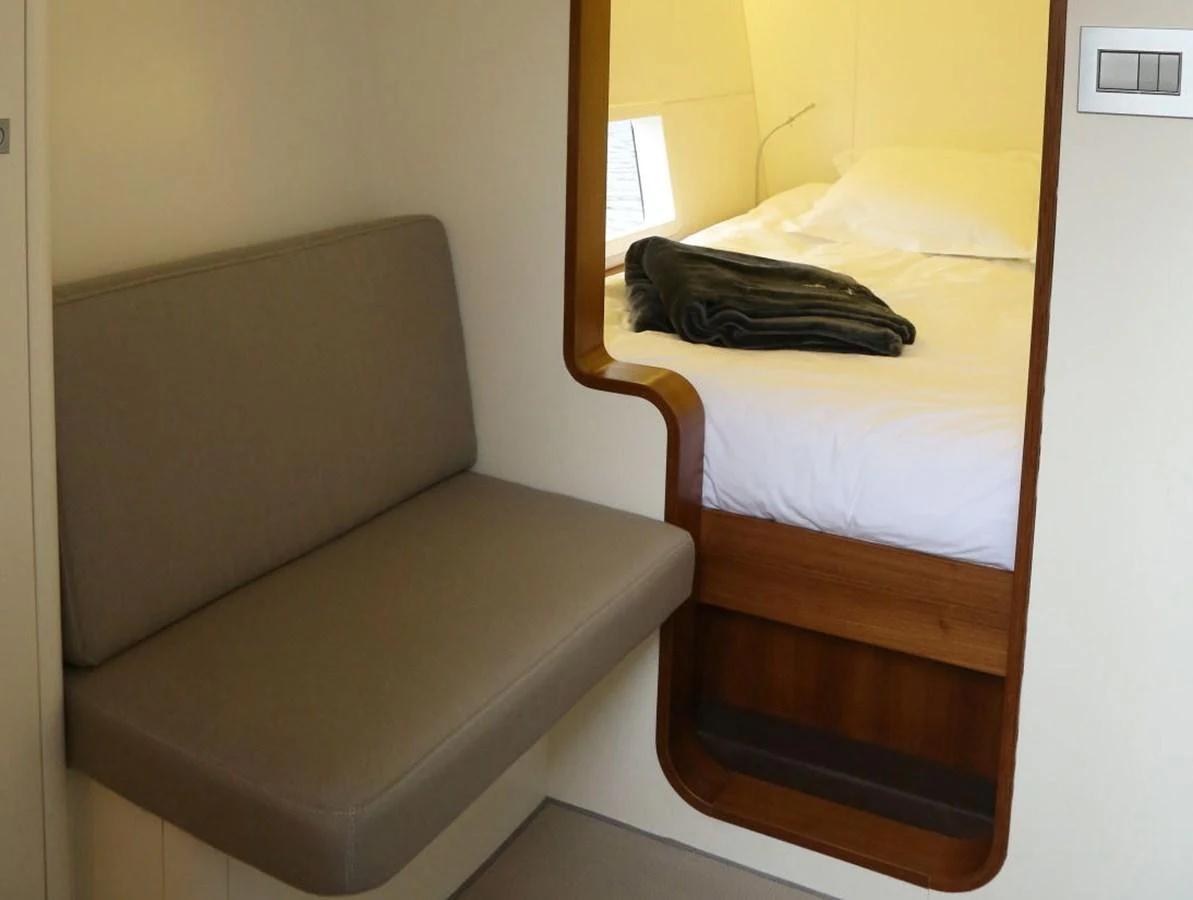 A cozy cabin with a comfortable bed and a small seating area. aboard VITALIA II Yacht for Sale