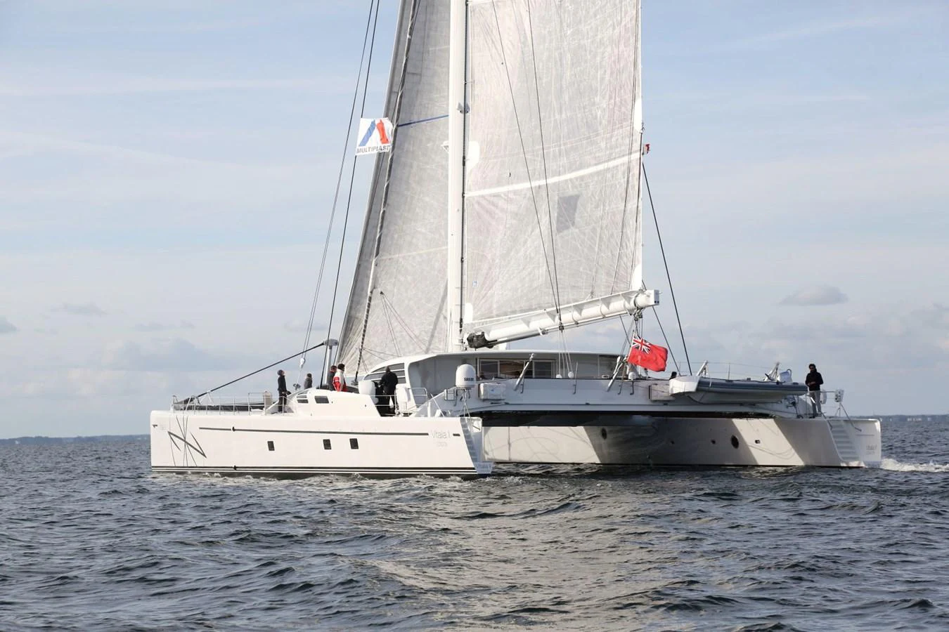 A sleek catamaran yacht sails gracefully on calm waters under a clear sky. aboard VITALIA II Yacht for Sale