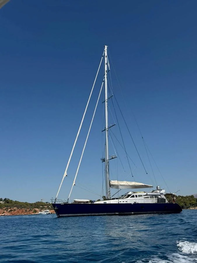 A sleek sailing yacht glides gracefully on calm waters under a clear blue sky. aboard PATRIOT Yacht for Sale
