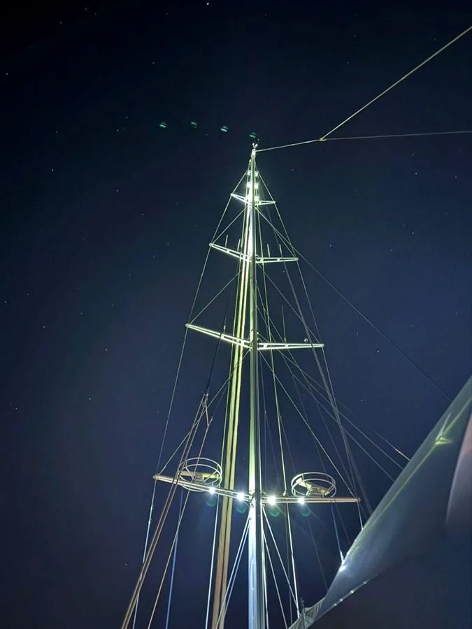 A night view of the yacht's mast illuminated against the dark sky. aboard PATRIOT Yacht for Sale