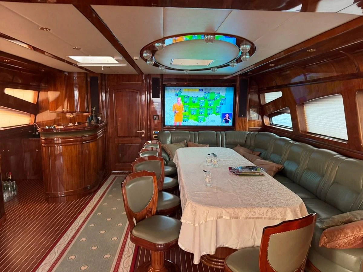 The yacht's saloon features a spacious seating area with a large table and a flat-screen TV for entertainment. aboard PATRIOT Yacht for Sale