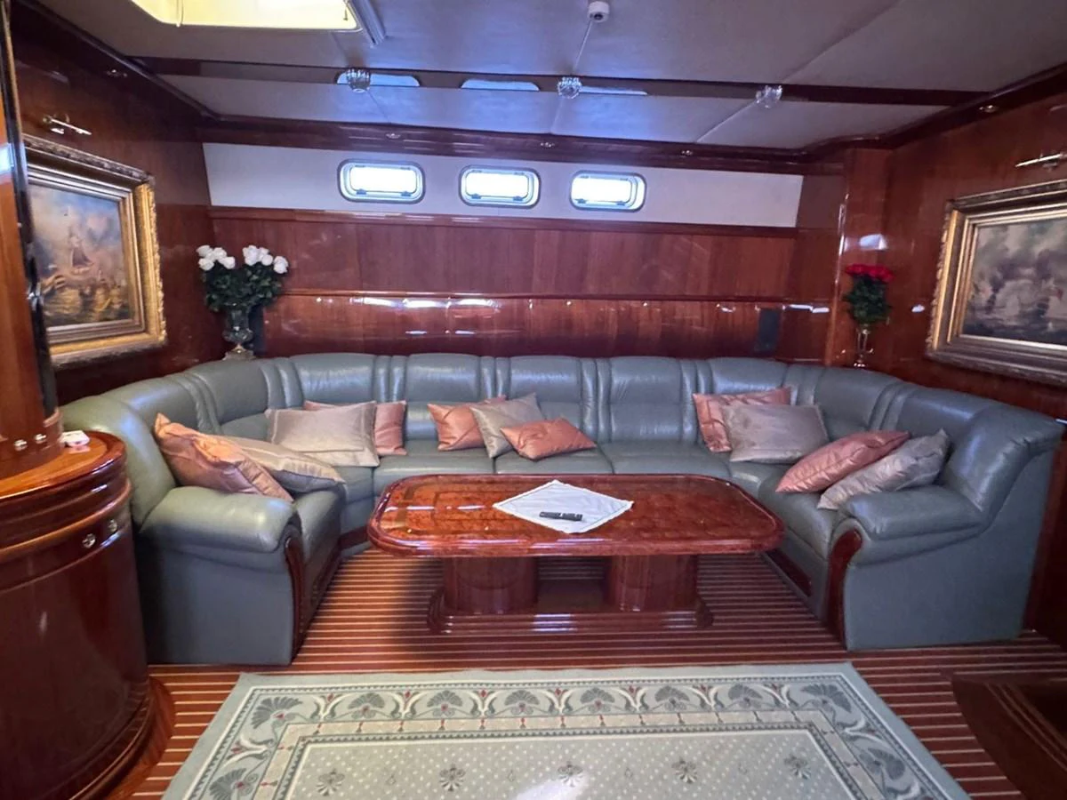 The yacht's salon features a plush, curved seating area with elegant wood finishes and tasteful decor. aboard PATRIOT Yacht for Sale