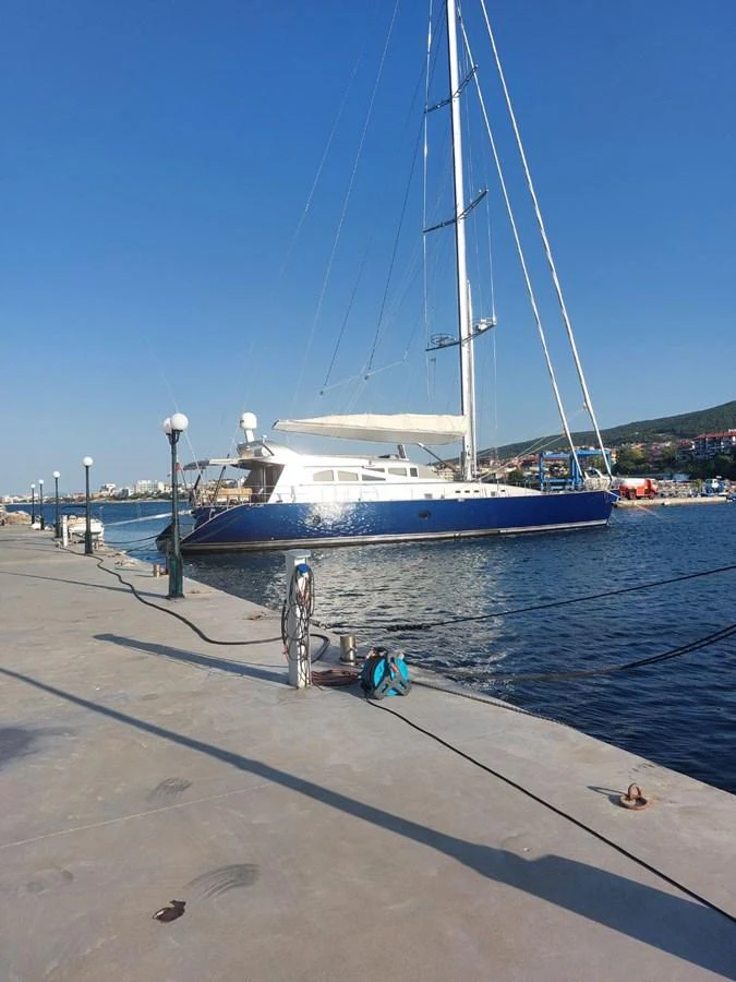 A sleek yacht is docked at the marina under a clear blue sky. aboard PATRIOT Yacht for Sale