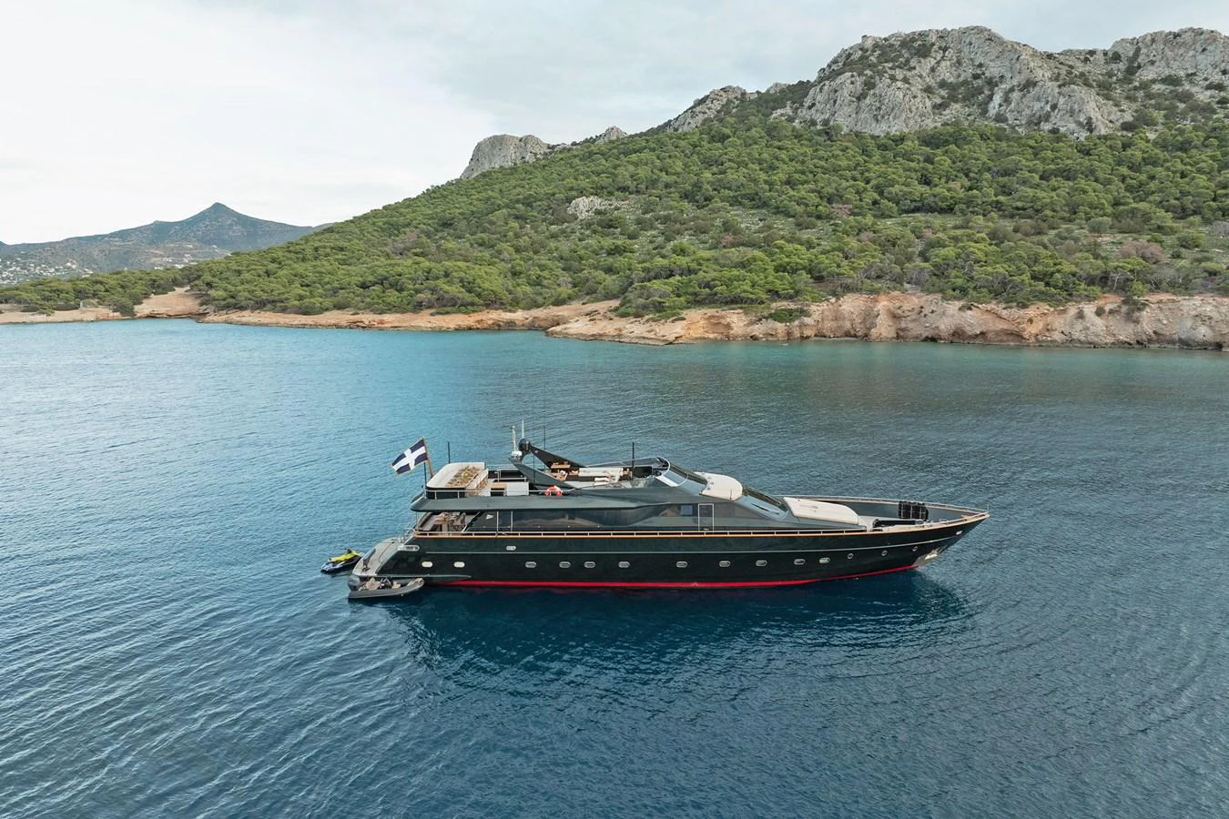 A sleek yacht cruises along a serene coastline with lush greenery and rugged hills in the background. aboard CAN'T REMEMBER Yacht for Sale