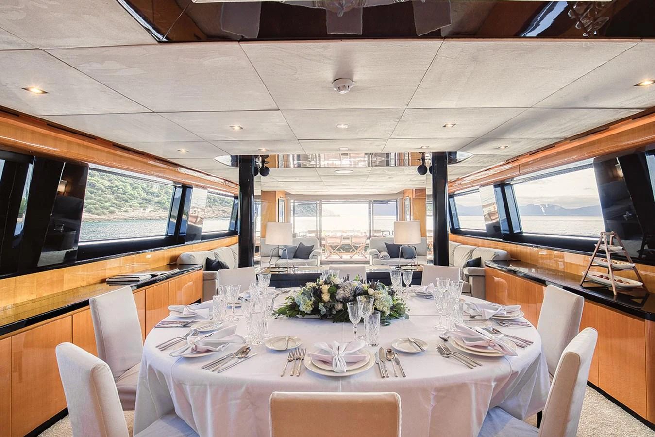 The yacht's dining area features an elegantly set table with panoramic views through large windows. aboard CAN'T REMEMBER Yacht for Sale