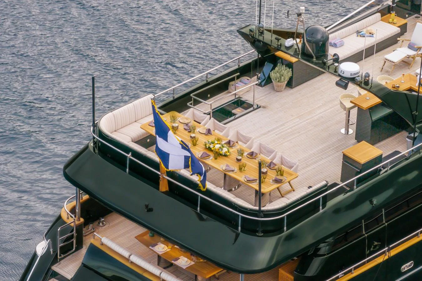 The yacht's aft deck features an elegant dining area with a beautifully set table, surrounded by comfortable seating and overlooking the water. aboard CAN'T REMEMBER Yacht for Sale