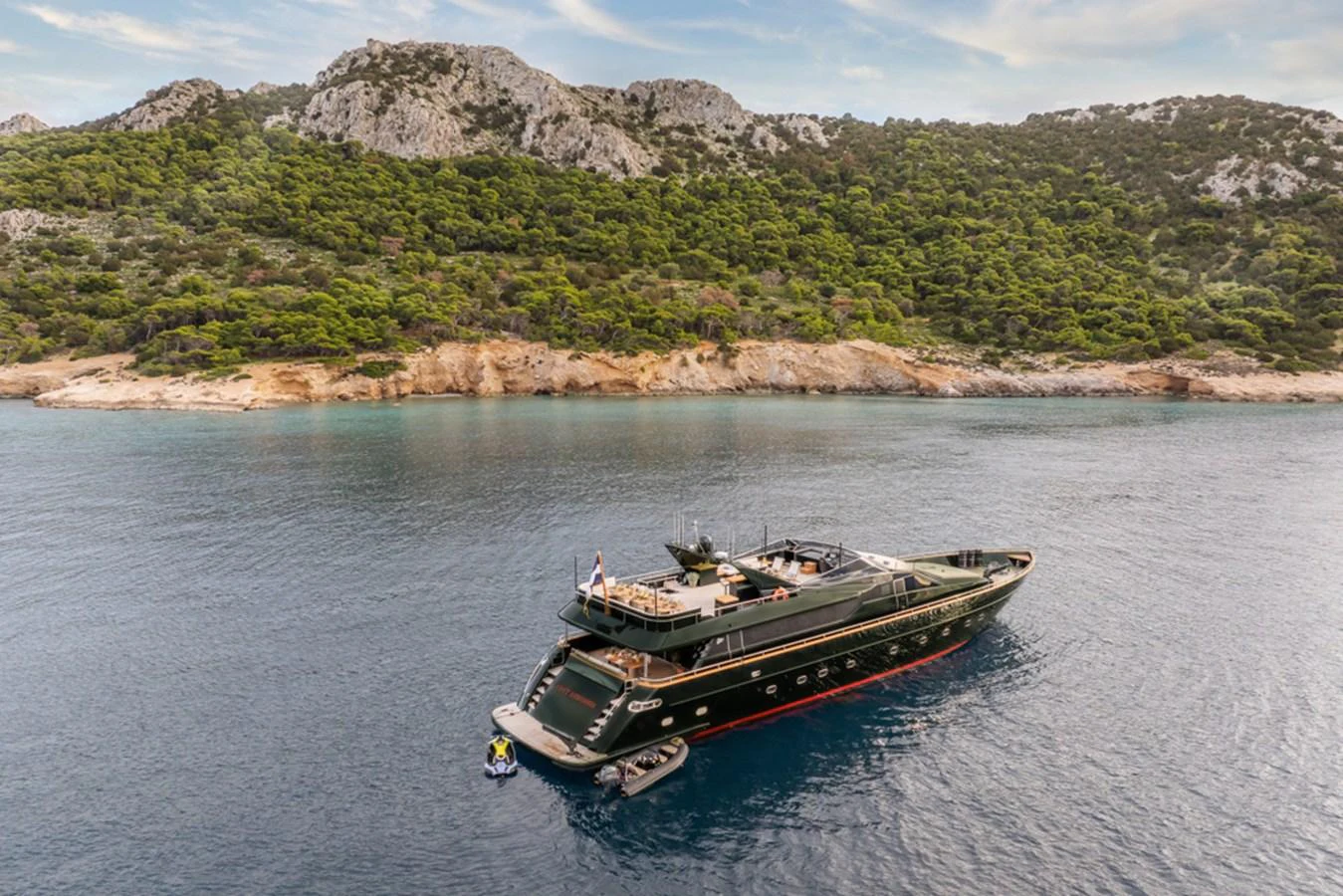 A luxurious yacht is anchored in a serene bay with a picturesque mountainous backdrop. aboard CAN'T REMEMBER Yacht for Sale
