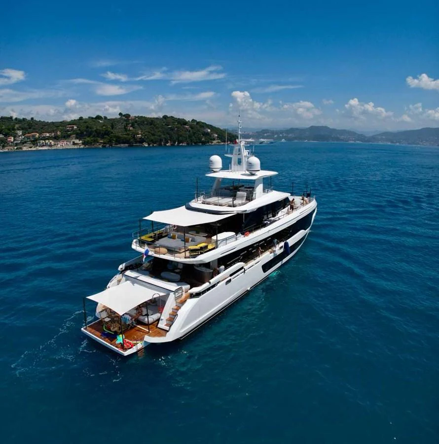A luxurious yacht cruising on a serene blue sea with a scenic coastline in the background. aboard LUZ DE MAR Yacht for Sale
