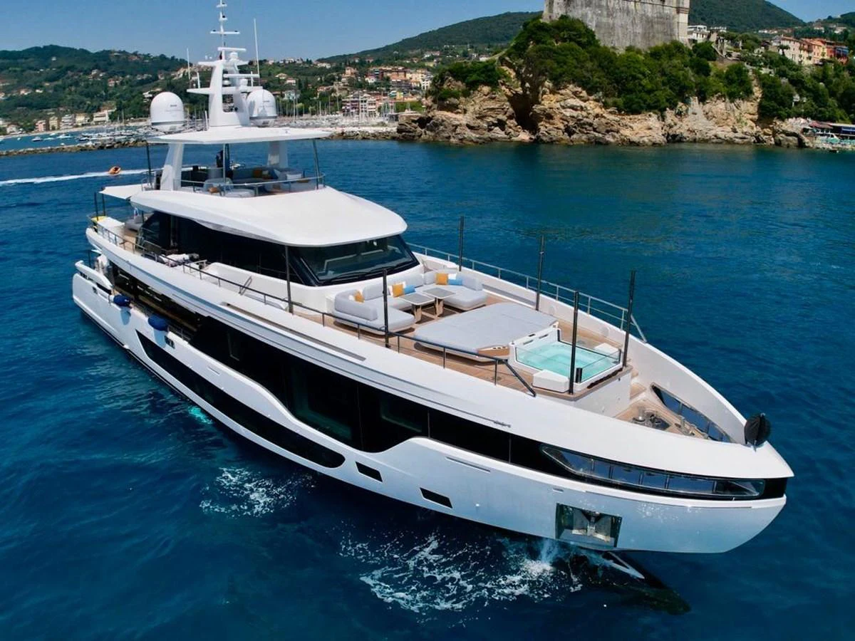 A sleek and modern yacht cruising in clear blue waters with a scenic coastal backdrop. aboard LUZ DE MAR Yacht for Sale