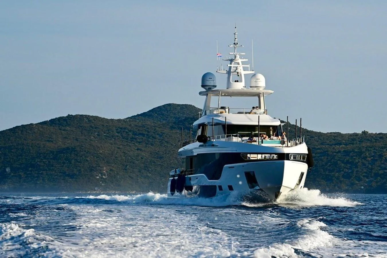 A luxurious yacht cruises through the open water with scenic hills in the background. aboard LUZ DE MAR Yacht for Sale