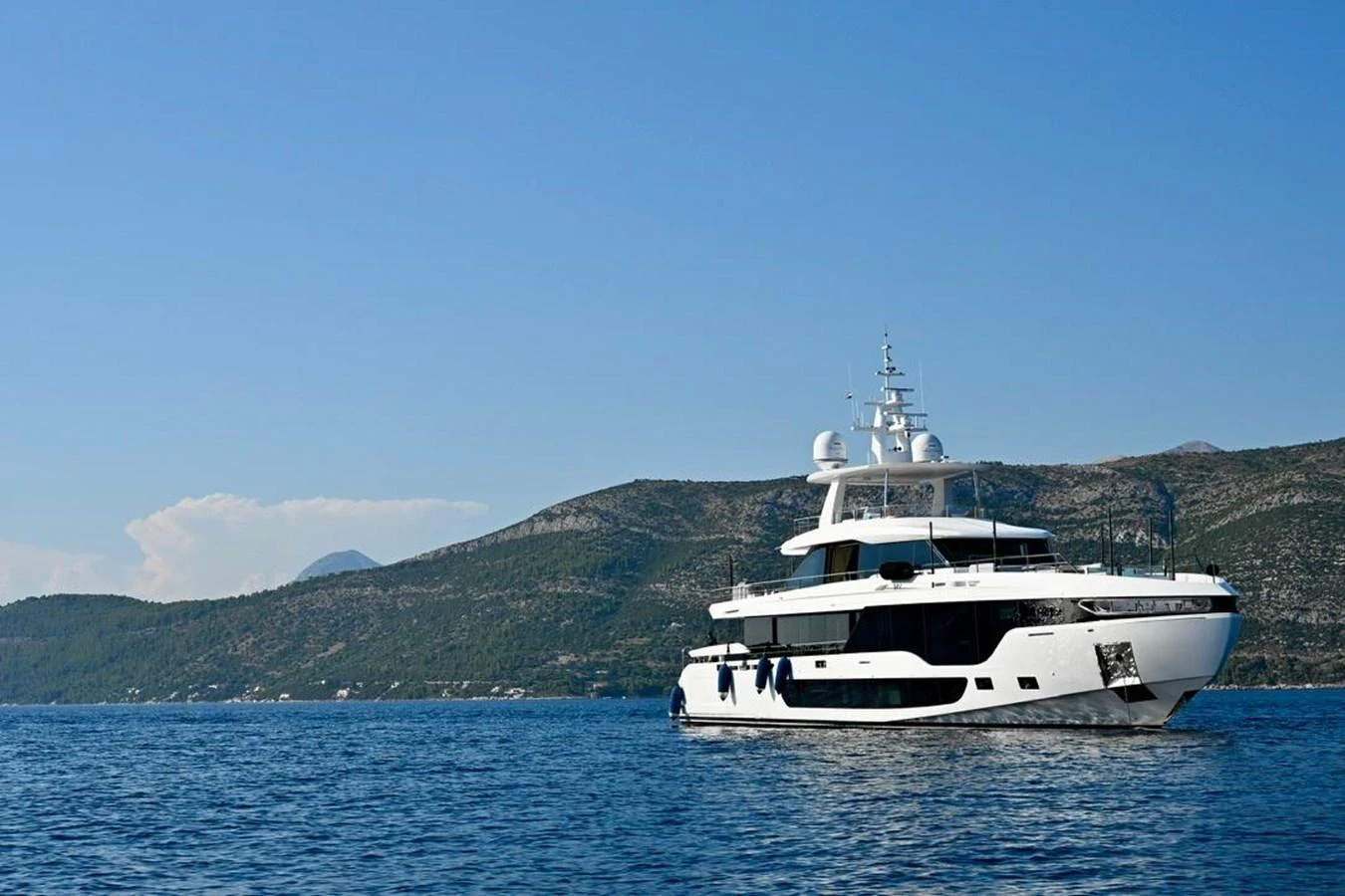 A luxurious yacht cruises through serene waters with a picturesque mountainous backdrop. aboard LUZ DE MAR Yacht for Sale