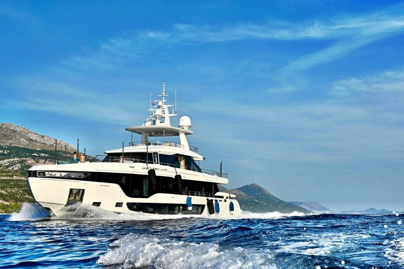A sleek and modern yacht cruises through clear blue waters against a scenic backdrop. aboard LUZ DE MAR Yacht for Sale