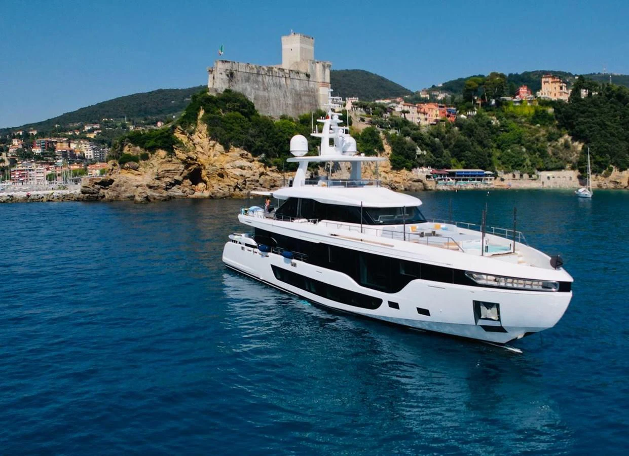A sleek, modern yacht cruises in clear blue waters with a scenic coastal backdrop. aboard LUZ DE MAR Yacht for Sale