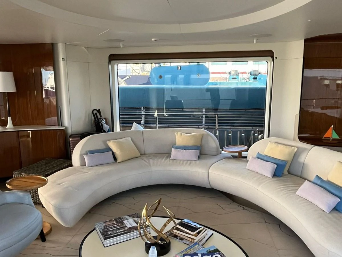 The salon features a spacious and elegant seating area with a modern, curved sofa and stylish decor. aboard LUZ DE MAR Yacht for Sale