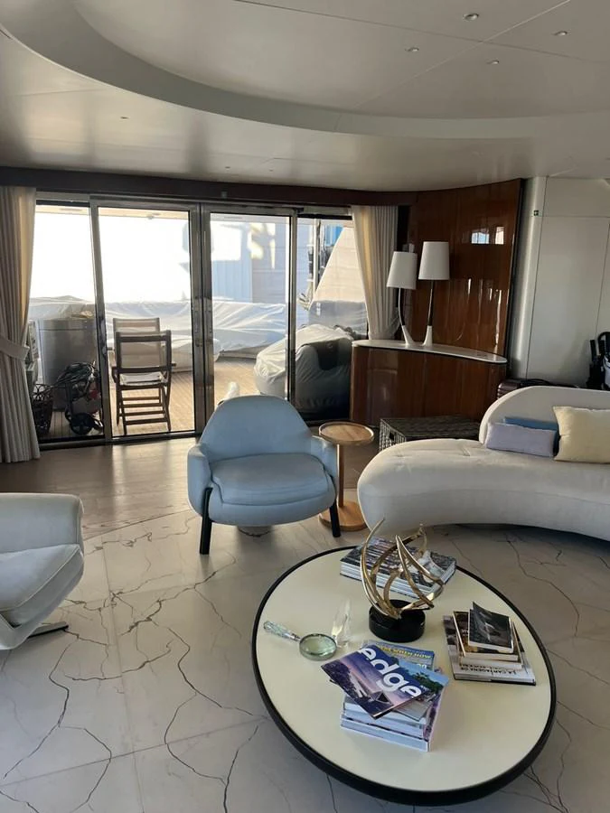 A stylish and modern yacht interior featuring comfortable seating and a coffee table with magazines. aboard LUZ DE MAR Yacht for Sale