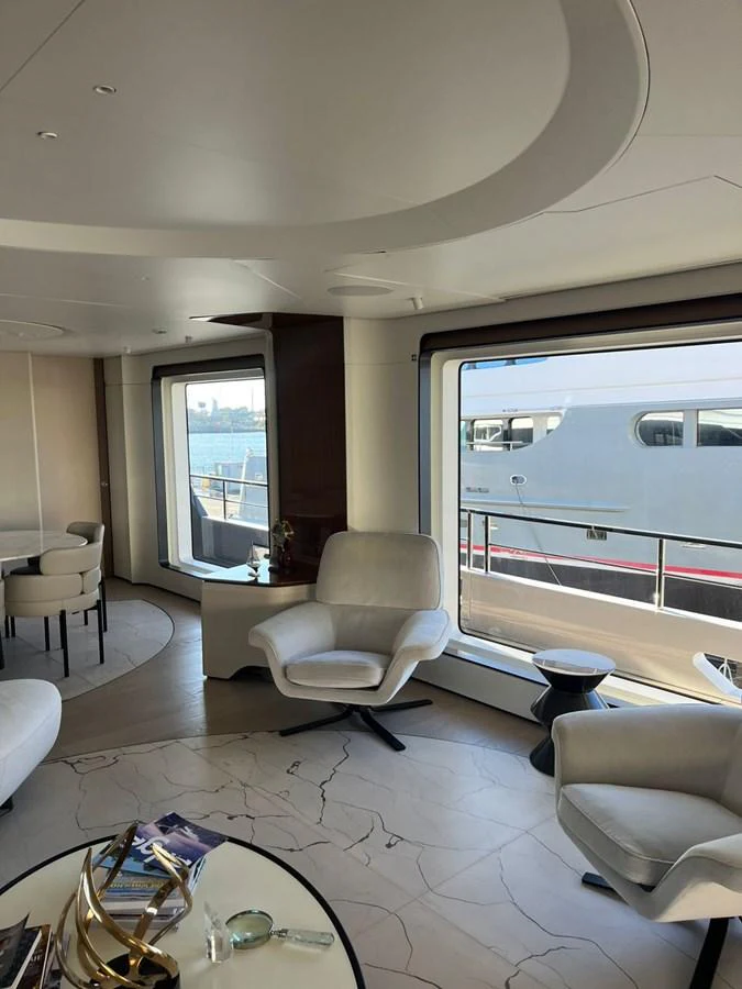 The salon features large windows with a view of the water, comfortable seating, and elegant decor. aboard LUZ DE MAR Yacht for Sale