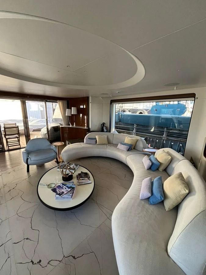 The yacht's salon features a curved sofa with plush cushions and a modern coffee table, creating a cozy and inviting atmosphere. aboard LUZ DE MAR Yacht for Sale