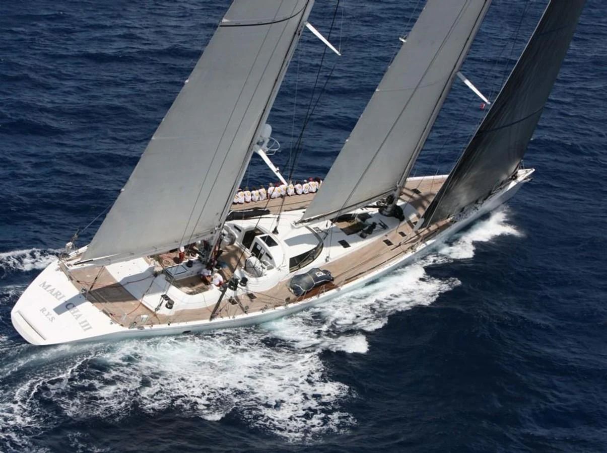 A sleek sailing yacht glides effortlessly through the open sea, showcasing its elegant design and powerful sails. aboard MARI-CHA III Yacht for Sale