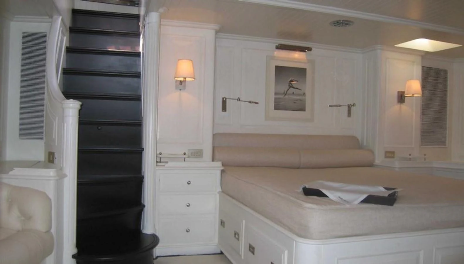 A luxurious stateroom featuring a large bed, elegant lighting, and a staircase leading to another level. aboard MARI-CHA III Yacht for Sale